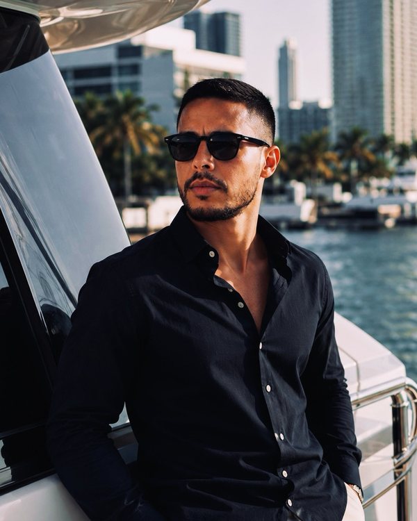 Rodrigo Reyes, Founder of Golden Anchor U.S, aboard a yacht on Biscayne Bay with the Miami skyline behind him